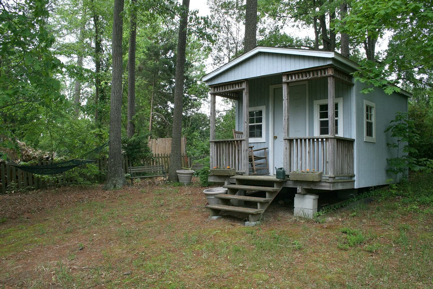 A small backyard building with a front porch among trees